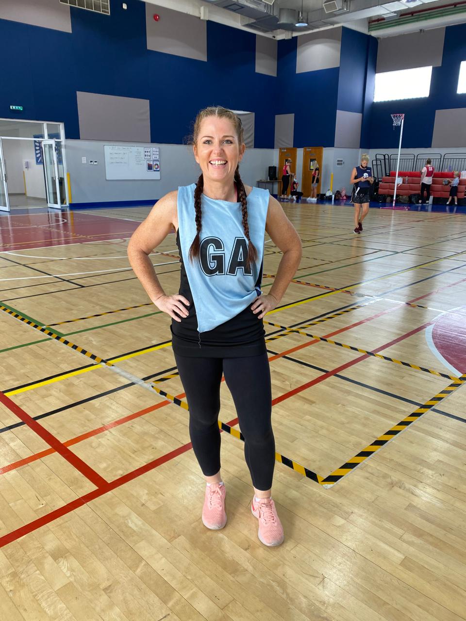 Andrea in netball kit on an indoor court