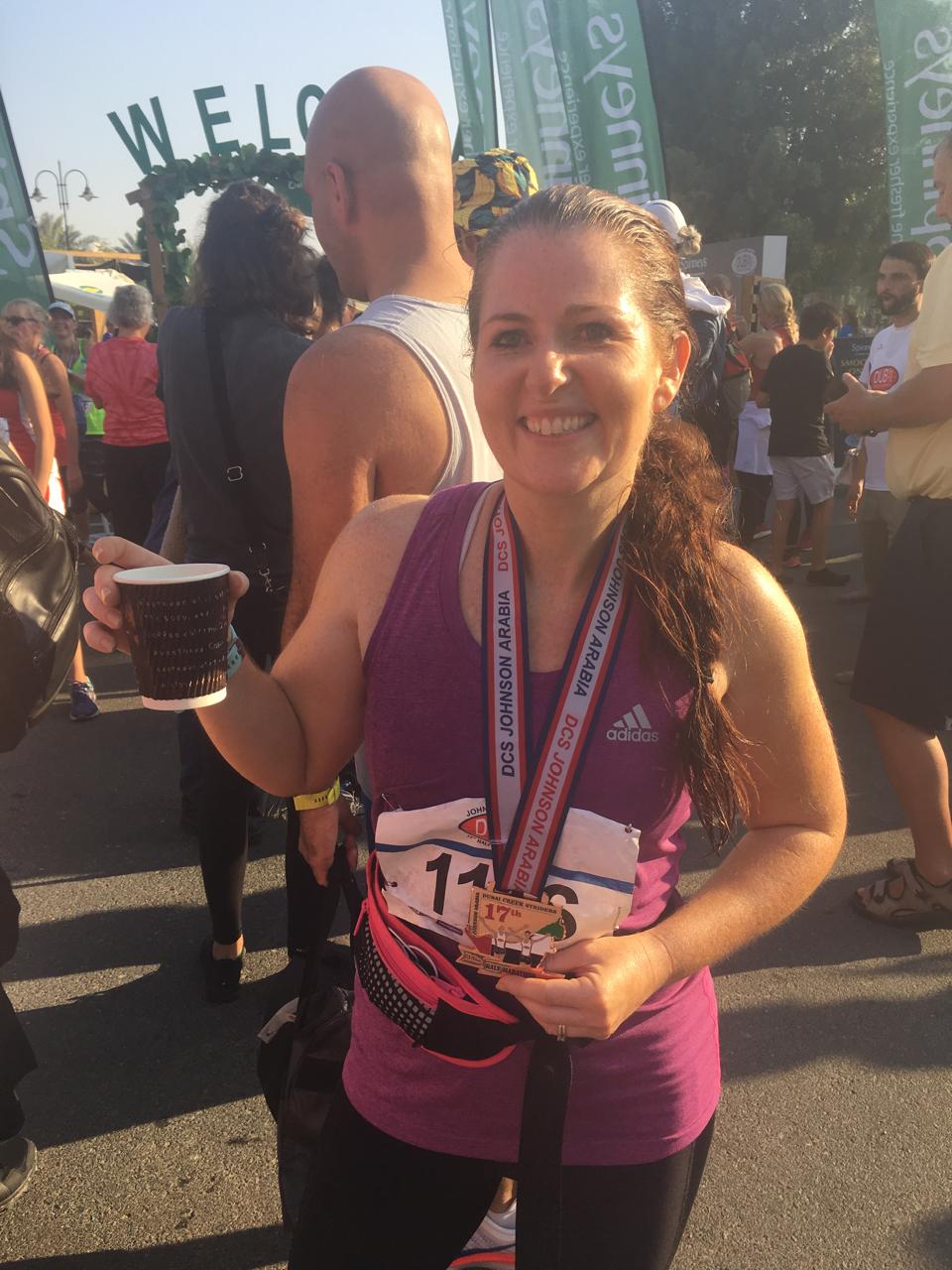 Andrea with a race medal and coffee after a road race in Dubai